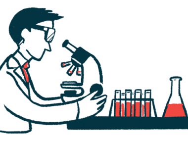 A researcher looks into microscope that's sitting next to a rack of filled test tubes and a beaker.